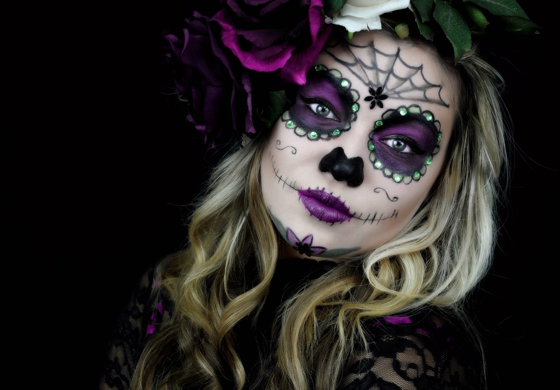 Artistic sugar skull makeup with purple and black accents on a woman’s face, styled with flowers, featured as an HD PC desktop wallpaper and background.