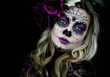 Artistic sugar skull makeup with purple and black accents on a woman’s face, styled with flowers, featured as an HD PC desktop wallpaper and background.