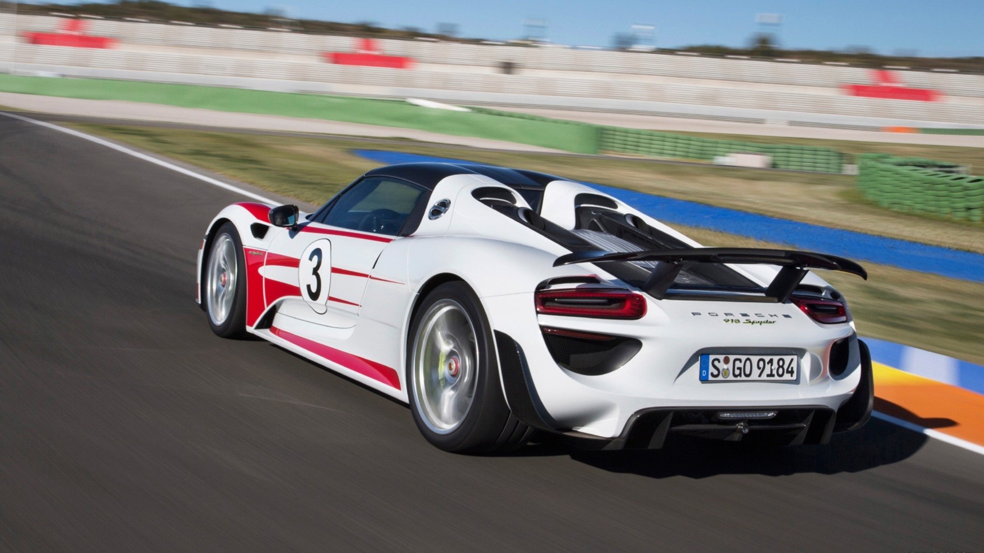 Rear three-quarter view of a white Porsche 918 Spyder race-liveried vehicle on a racetrack — HD PC desktop wallpaper and background.