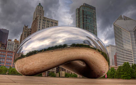 Reflective bean-shaped man-made sculpture in Chicago with skyline and stormy sky, presented as a 2K Quad HD PC desktop wallpaper and background.