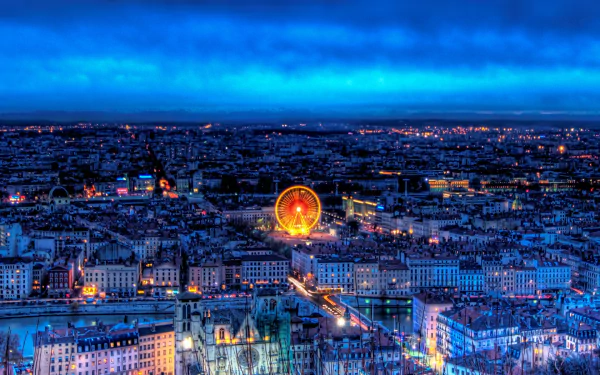 Nighttime cityscape of Lyon, France, showcasing illuminated buildings and a glowing Ferris wheel, captured in HD for a vivid desktop wallpaper background.
