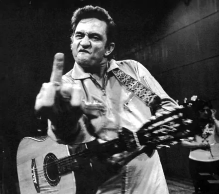 A striking black and white wallpaper of Johnny Cash passionately performing with his guitar, capturing the essence of his rebellious spirit and musical legacy.