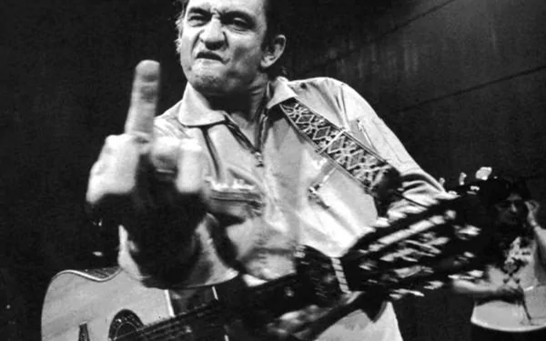 A striking black and white wallpaper of Johnny Cash passionately performing with his guitar, capturing the essence of his rebellious spirit and musical legacy.