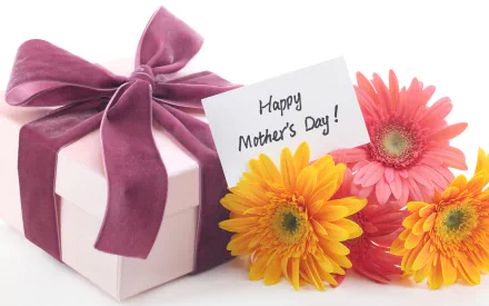 HD desktop wallpaper showing a Mother's Day gift box with a purple ribbon, accompanied by colorful gerbera daisies and a handwritten Happy Mother's Day! card.