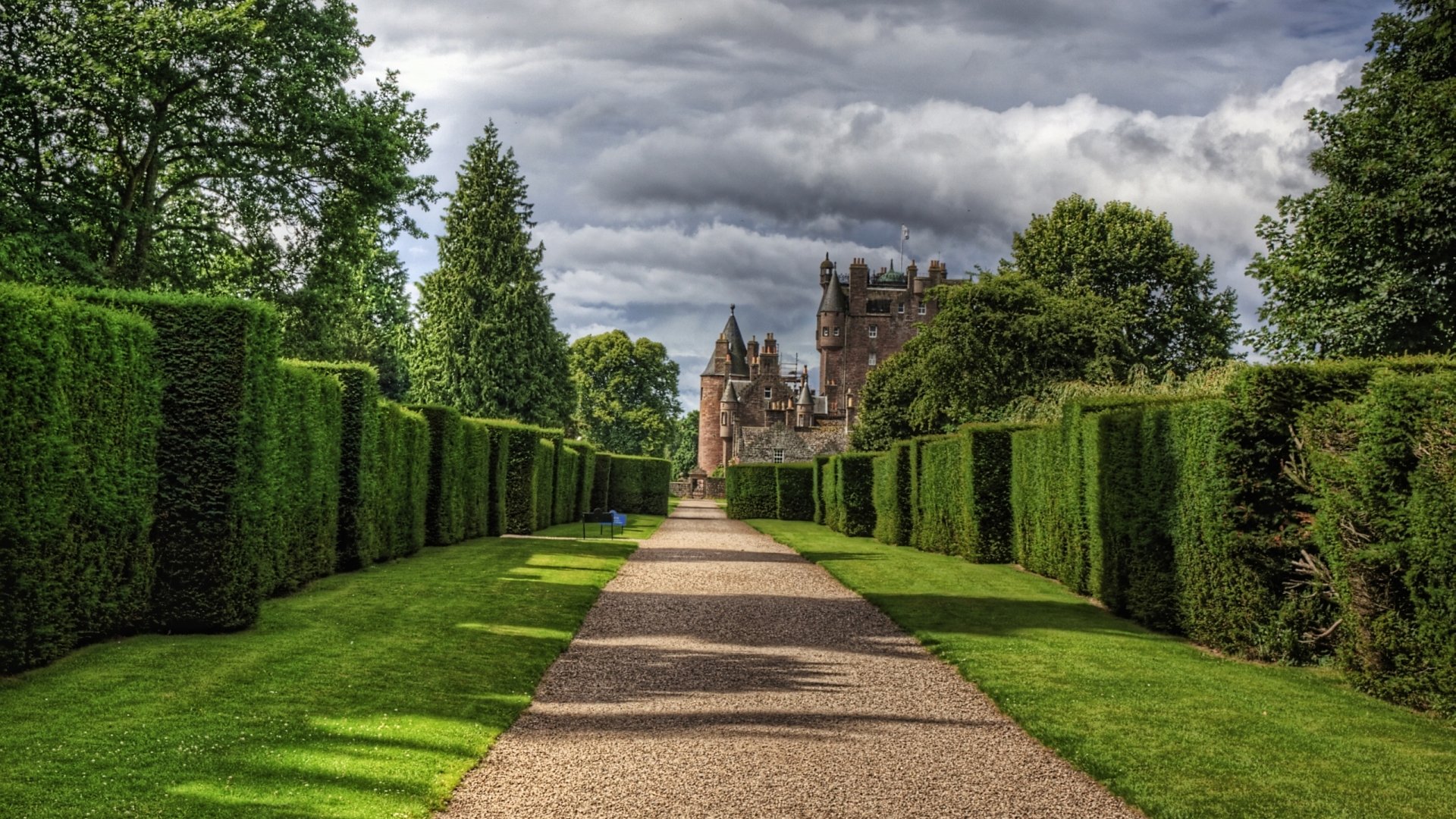 HD PC desktop wallpaper showcasing Glamis Castle framed by neatly trimmed hedges under a cloudy sky, blending natural and man-made beauty.