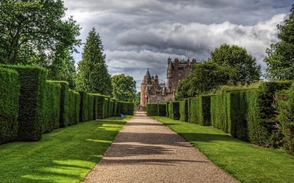 HD PC desktop wallpaper showcasing Glamis Castle framed by neatly trimmed hedges under a cloudy sky, blending natural and man-made beauty.