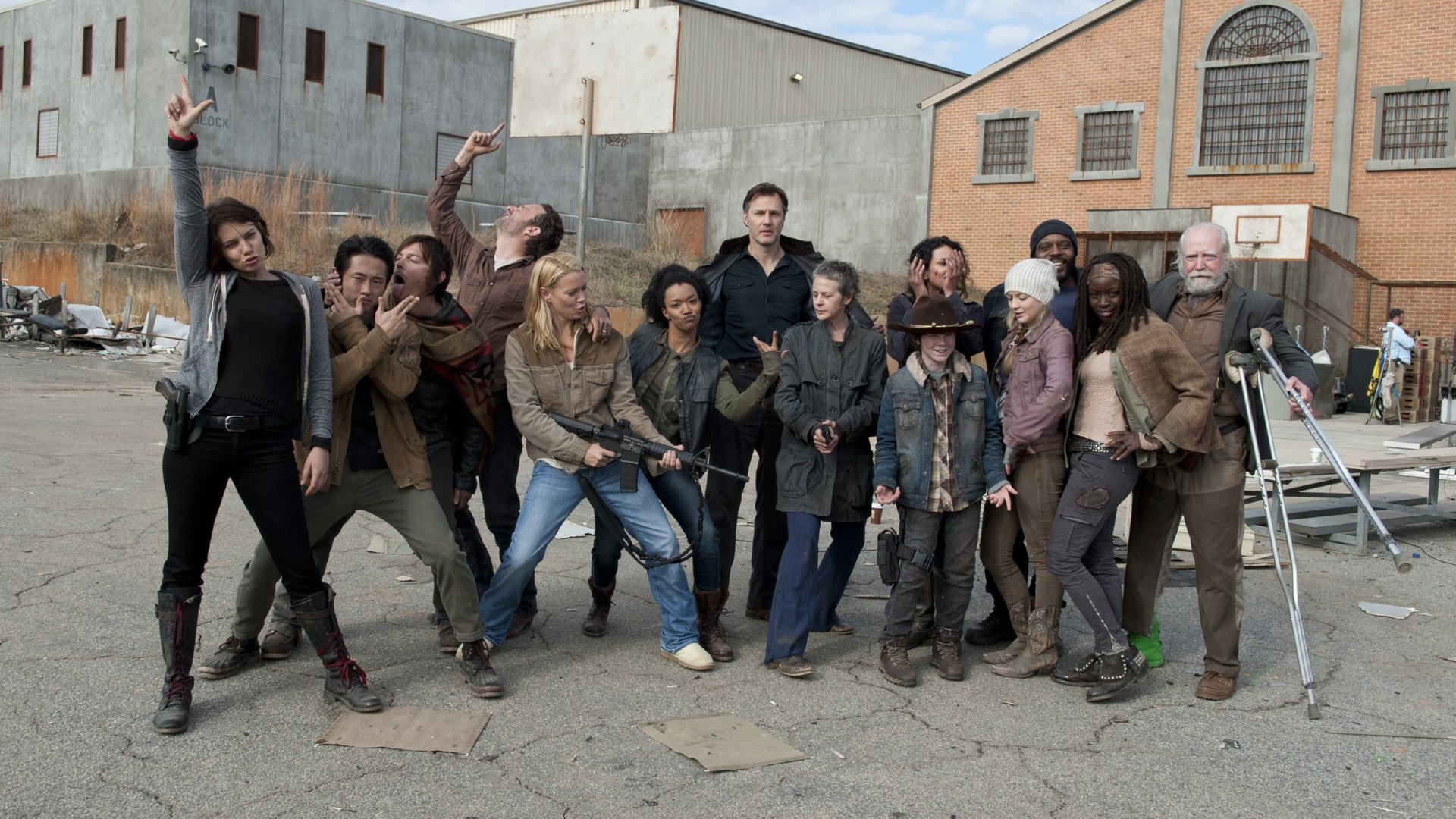 A group of characters from the TV show The Walking Dead poses playfully in an urban setting, creating a vibrant and dynamic HD desktop wallpaper.