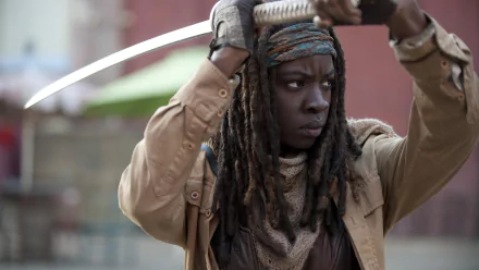 Michonne from The Walking Dead stands poised with a sword, reflecting her fierce and determined character in this HD desktop wallpaper from the popular TV show.