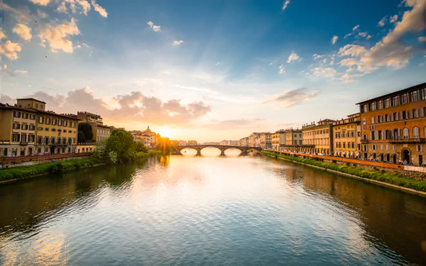 HD desktop wallpaper showcasing the man-made beauty of Florence with the Arno River and historic buildings under a colorful sunset sky.