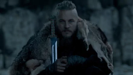 HD desktop wallpaper of Ragnar Lothbrok from the TV show Vikings, dressed in a fur cloak, holding a sword, with a dark and intense background.
