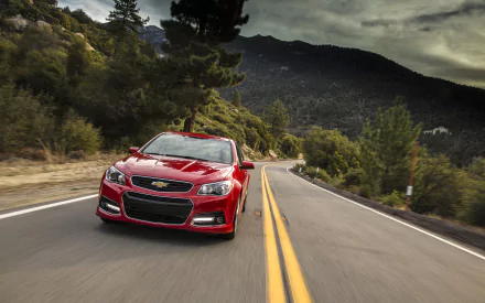 Red Chevrolet SS vehicle on a winding mountain road under dramatic clouds — 2K Quad HD PC desktop wallpaper and background