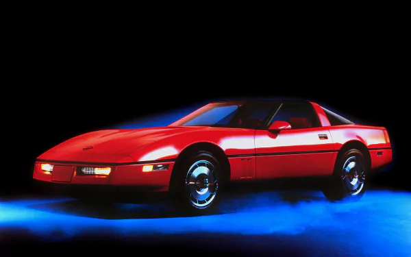 Red Chevrolet Corvette (C4) sports vehicle on a blue-lit black background — HD PC desktop wallpaper/background.