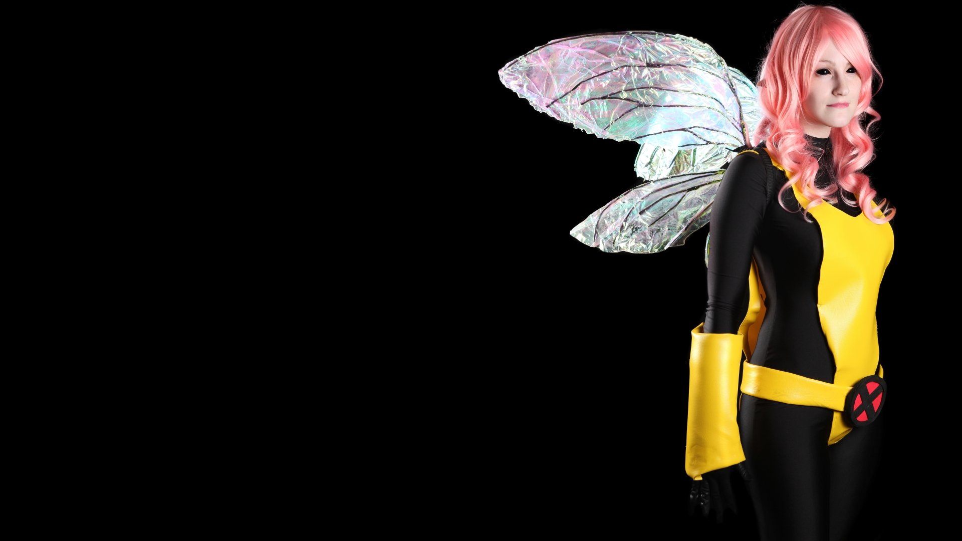 8K Ultra HD PC desktop wallpaper: woman cosplayer with pink hair, iridescent fairy wings and a black-and-yellow superhero-style costume against a black background.