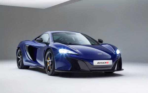 Blue McLaren 650S supercar pictured in a clean studio, sleek lines and lit headlights — HD PC desktop wallpaper and vehicle background.
