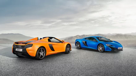 Two McLaren 650S supercars, one orange and one blue, parked on a wide open asphalt surface under a cloudy sky in this HD PC desktop wallpaper.