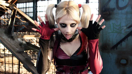 4K Ultra HD PC desktop wallpaper of a woman cosplaying Harley Quinn: bleached pigtails, heavy eye makeup, tongue out, red-and-black costume in a gritty industrial background.