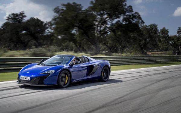 Blue McLaren 650S Spider supercar driving on a racetrack with trees in the background, captured as an HD desktop wallpaper.