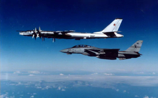 Military aircraft Tupolev Tu-95 and a fighter jet flying side by side above the clouds, captured in a high-definition desktop wallpaper.