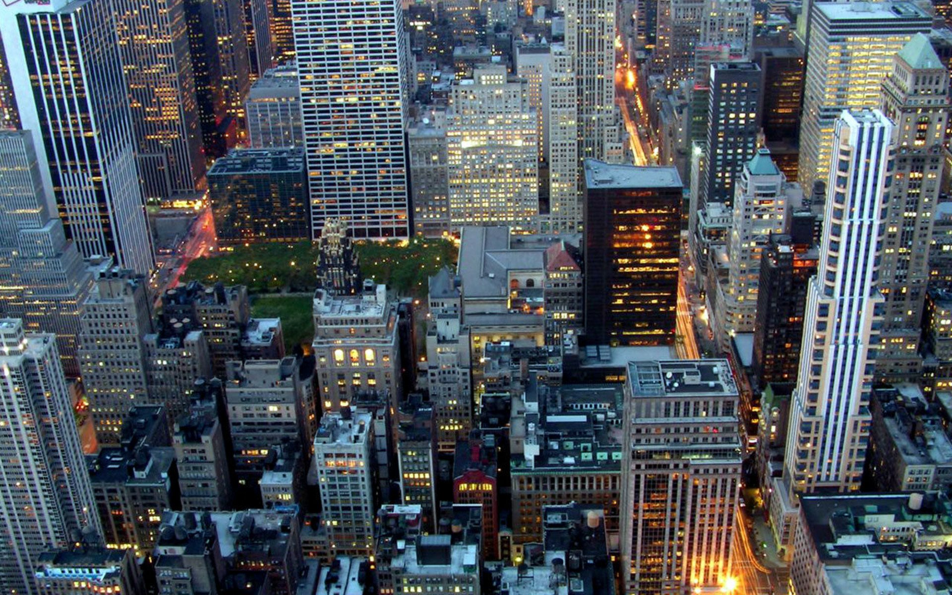 Aerial HD PC desktop wallpaper and background of New York's dense man-made skyline at dusk, glowing skyscrapers and lit grid streets forming a vibrant urban mosaic.