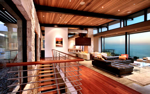 A modern man-made room featuring wooden ceilings, stone walls, and large windows overlooking a sunset, captured in 4K Ultra HD for PC desktop wallpaper.