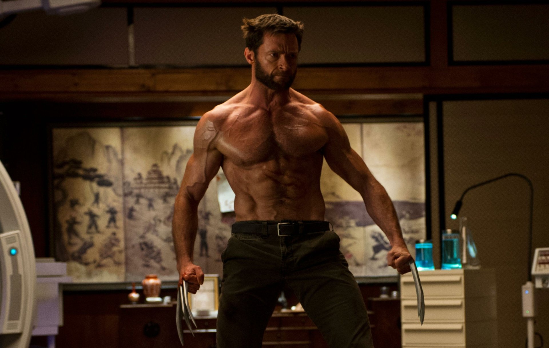 HD desktop wallpaper featuring a muscular Wolverine from the movie The Wolverine, standing shirtless with claws extended in a dimly lit room.