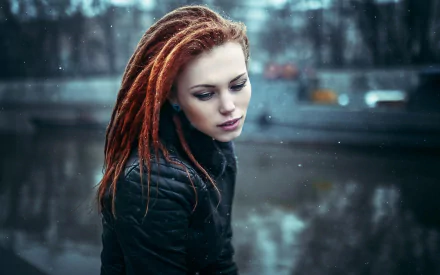 HD PC desktop wallpaper featuring a woman with red dreadlocks in a contemplative mood against a blurred, snowy urban background.