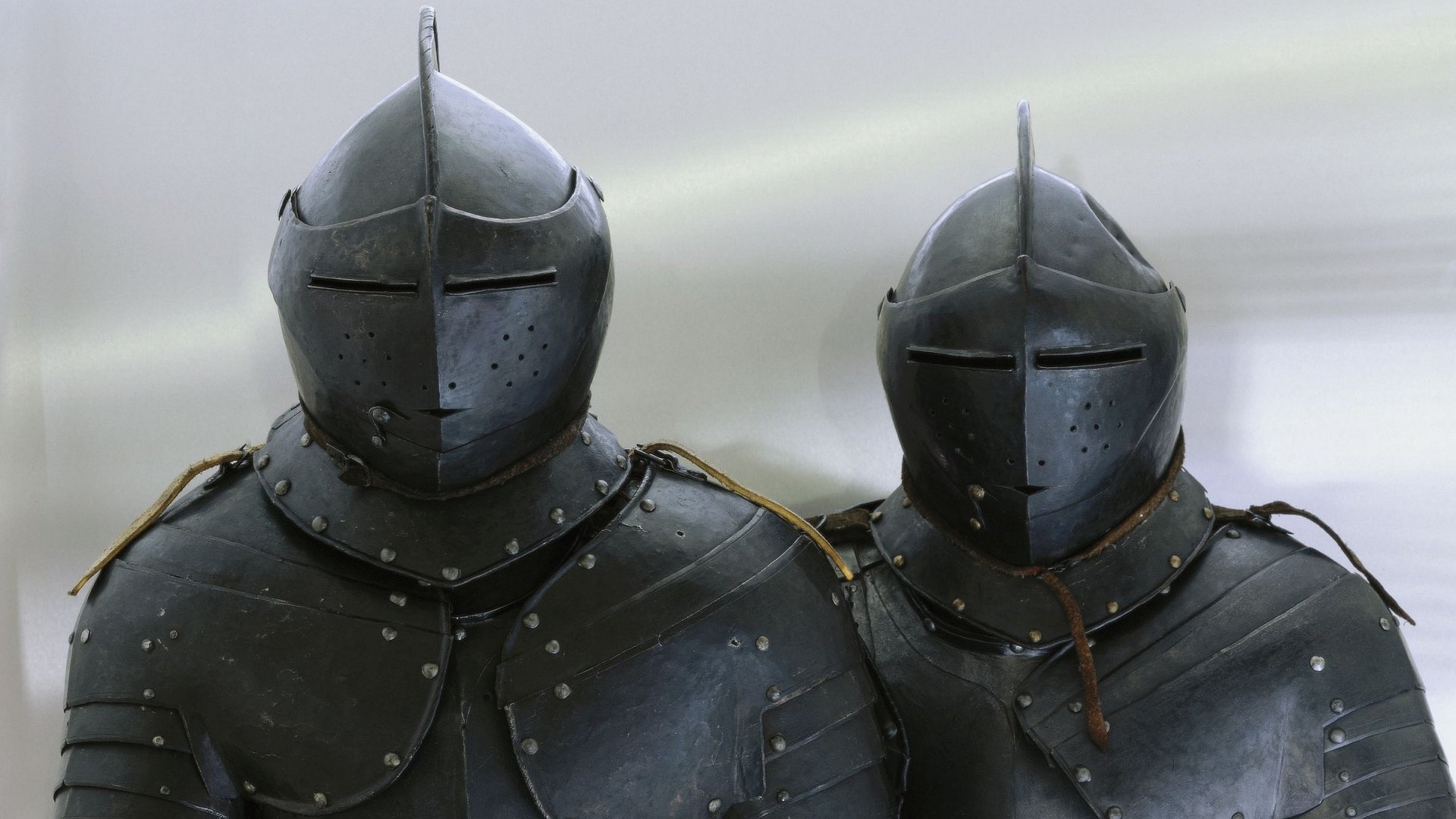 HD PC desktop wallpaper background: two man-made medieval steel suits of armor standing side by side against a soft gray backdrop.