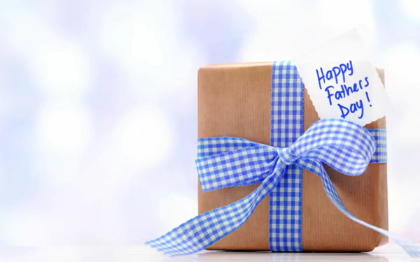 Father's Day themed HD desktop wallpaper with a gift wrapped in brown paper and a blue checkered ribbon, tag reading Happy Father's Day!