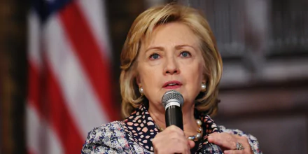 HD desktop wallpaper of a woman speaking into a microphone with an American flag in the background.