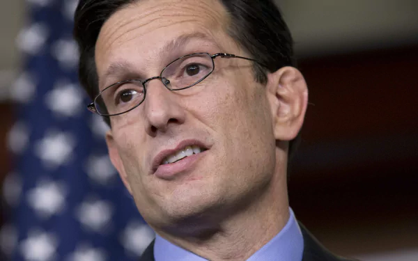 HD desktop wallpaper featuring a man in a suit with an American flag in the background.