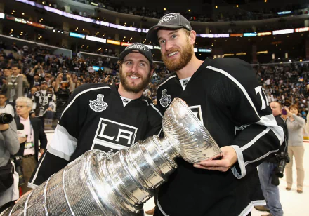 HD wallpaper of two Los Angeles Kings players smiling and posing with the Stanley Cup on the ice.