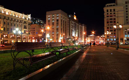 A beautiful nighttime scene featuring a row of benches along a well-lit walkway, surrounded by illuminated buildings and vibrant city life, ideal as an HD PC desktop wallpaper.