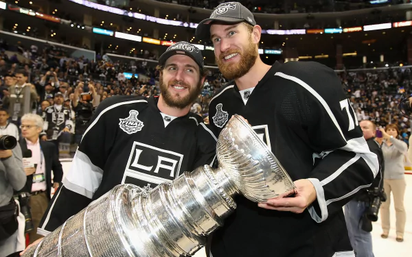 HD wallpaper of two Los Angeles Kings players smiling and posing with the Stanley Cup on the ice.