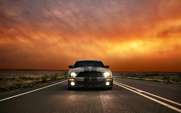 HD desktop wallpaper featuring a Ford Mustang Shelby Cobra GT 500 parked on an open road under a dramatic sunset sky.