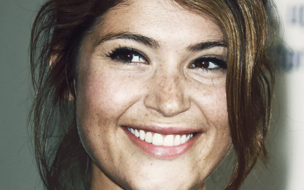 A close-up of Gemma Arterton featuring her brown eyes and freckles, radiating warmth with a bright smile. This HD image serves as a captivating desktop wallpaper.