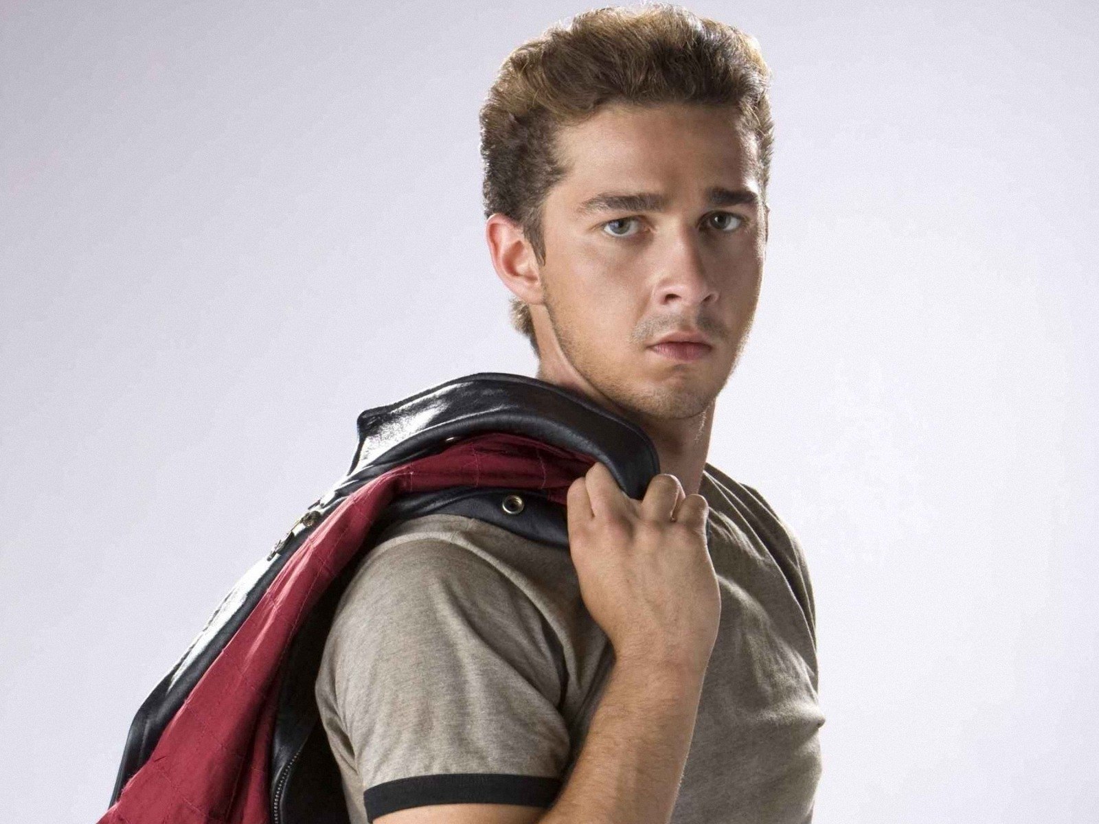 HD wallpaper featuring a man with a backpack looking over his shoulder with a serious expression.
