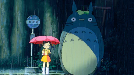 Mei Kusakabe stands under an umbrella beside Totoro in a rain-soaked scene from My Neighbor Totoro, depicted in vibrant HD as a captivating desktop wallpaper.