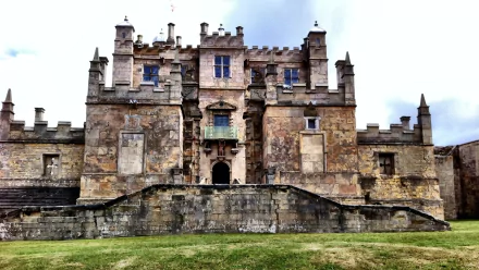 HD PC wallpaper of Bolsover Castle, a historic man-made stone fortress with detailed battlements under a cloudy sky.