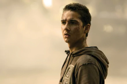 HD desktop wallpaper featuring a focused individual in a brown hoodie with a grimy backdrop.