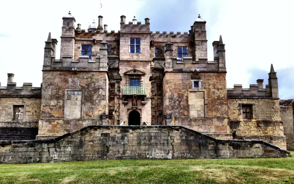 HD PC wallpaper of Bolsover Castle, a historic man-made stone fortress with detailed battlements under a cloudy sky.