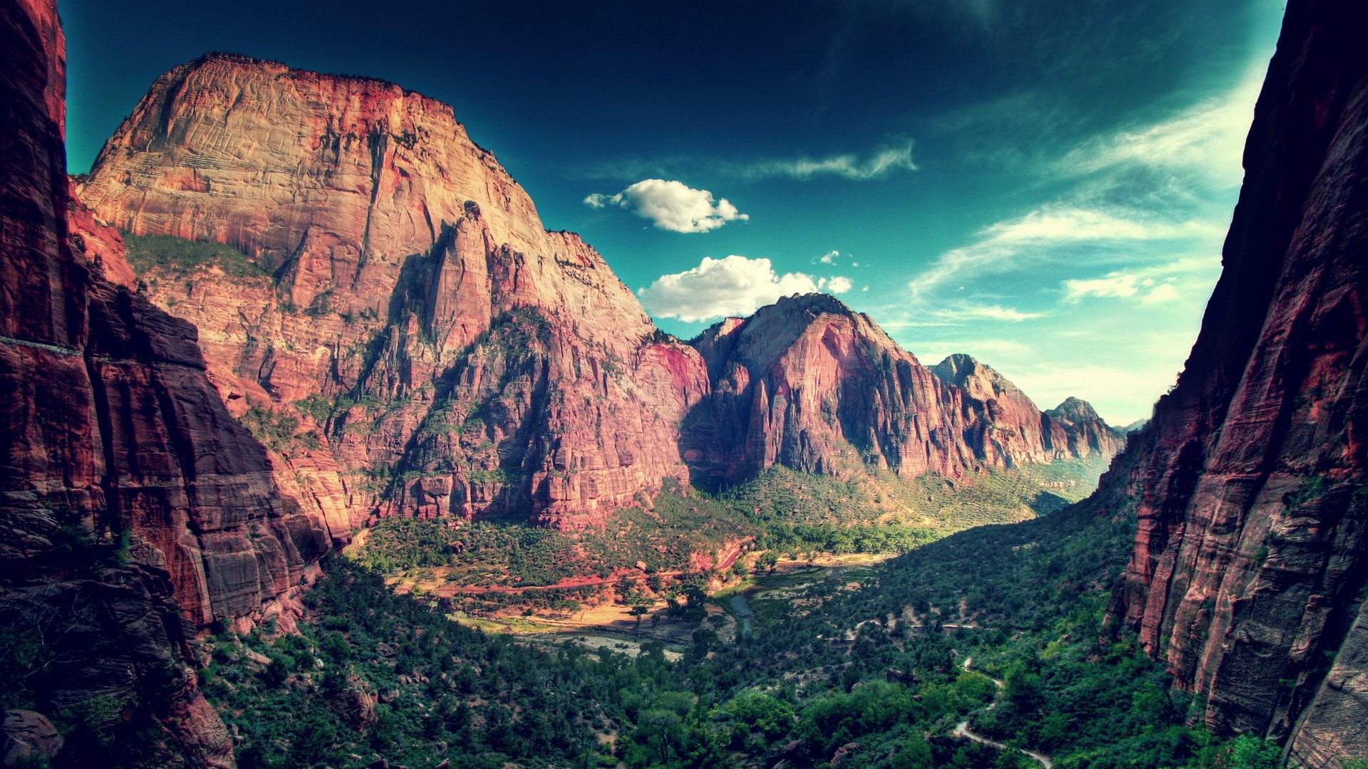 HD PC desktop wallpaper showing a nature canyon panorama: sunlit red-rock cliffs, verdant valley floor and dramatic teal sky.