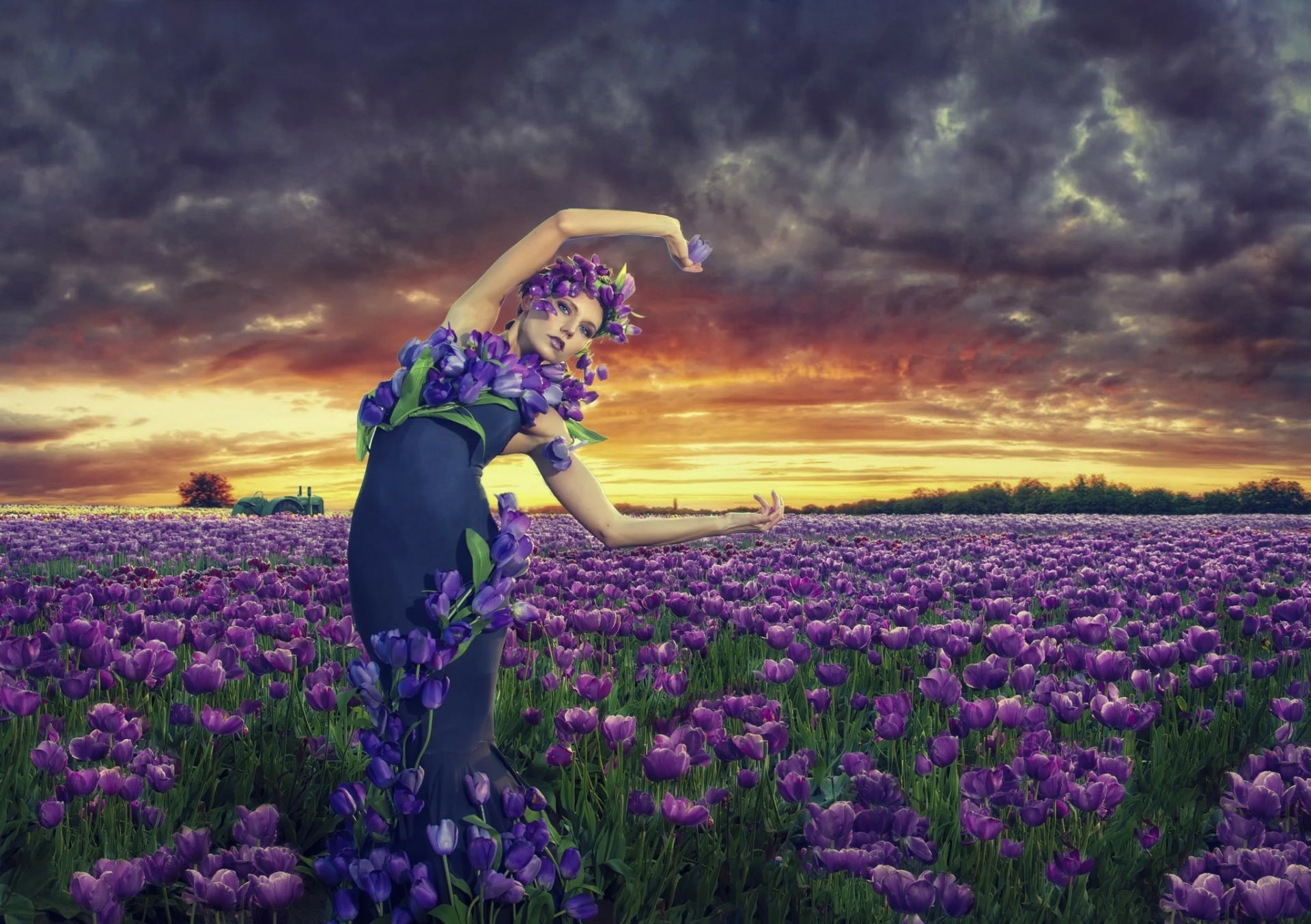 An artistic HD desktop wallpaper featuring a woman adorned with tulip flowers, posing gracefully in a field of tulips at sunrise, against a dramatic sky.