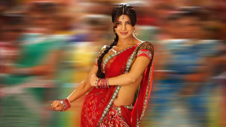 Priyanka Chopra shines in a vibrant red saree, embodying grace and elegance against a blurred background, celebrating her status as an iconic Indian celebrity and Miss World.