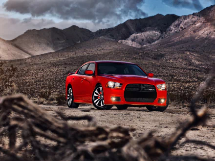 Red Dodge Charger SRT8 parked on a desert plain with rugged mountains under a dramatic sky — HD PC desktop wallpaper background.