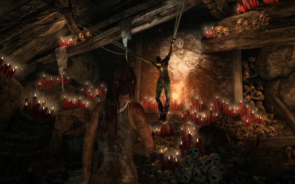 HD PC wallpaper from Tomb Raider (2013) featuring a dimly lit cavern with red candles, skulls, and a suspended figure, creating an intense and eerie atmosphere.