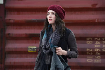 HD PC desktop wallpaper featuring Kat Dennings as Darcy Lewis from the movie Thor: The Dark World, wearing a red knit hat and dark scarf against a red industrial background.