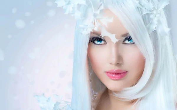 A woman with striking blue eyes and long white hair adorned with delicate snowflakes, set against a soft, ethereal backdrop—an enchanting HD desktop wallpaper.