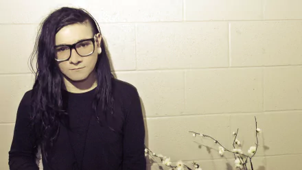 A high-definition wallpaper featuring Skrillex, a notable figure in music, posed in front of a textured wall with a minimalist aesthetic.