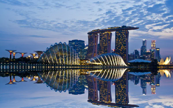 HD desktop wallpaper showcasing Singapore’s Marina Bay Sands and Gardens by the Bay at dusk with a clear reflection on the water.