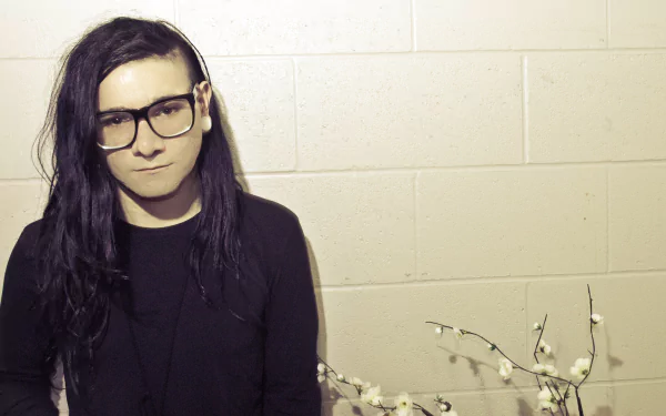 A high-definition wallpaper featuring Skrillex, a notable figure in music, posed in front of a textured wall with a minimalist aesthetic.